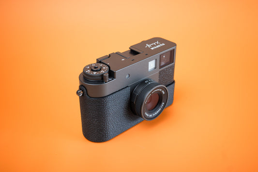Fujifilm X half in a black TPU Slim Skin no grip Case, front three-quarter view