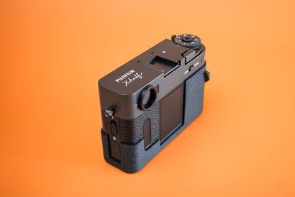 Fujifilm X half in Slim Skin Grip Case with thumb grip, left side profile showing leatherette-textured TPU