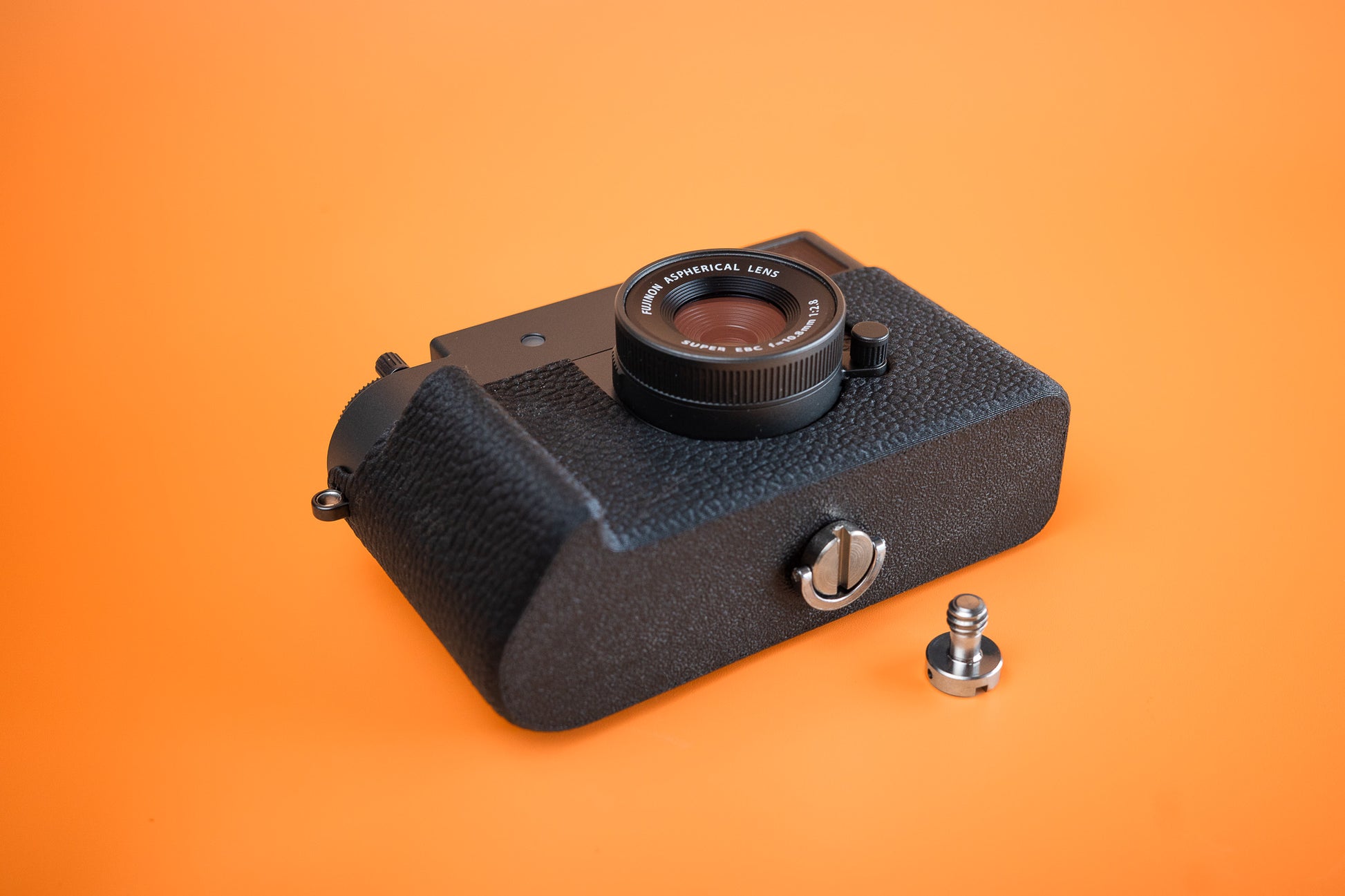 Fujifilm X half in Slim Skin Case with grip, angled view showing grip and base of the tripod version case with extra longer screw