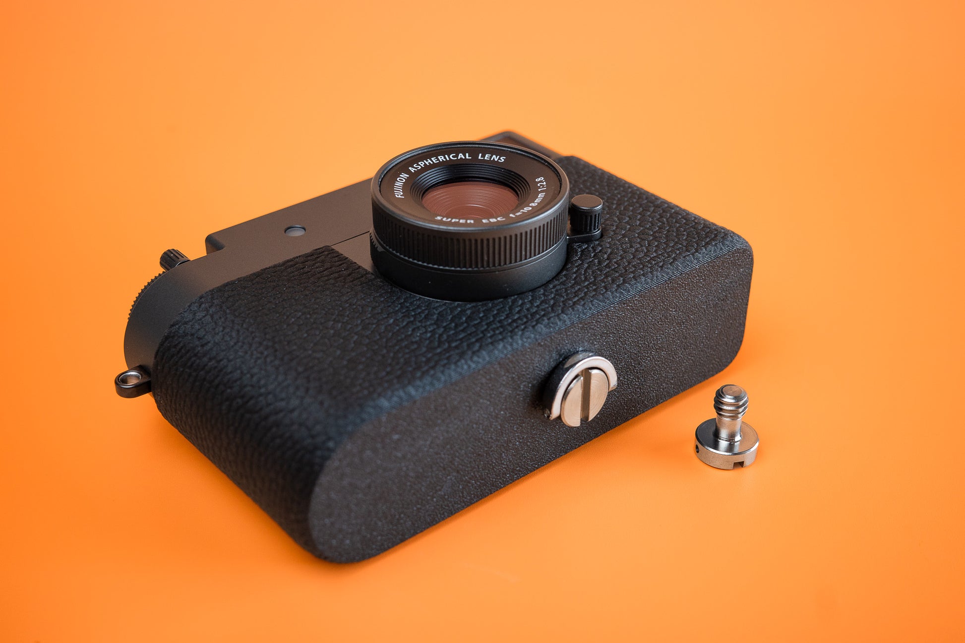 Fujifilm X half in Slim Skin Case with no grip, angled view showing front and base of the tripod version case with extra longer screw