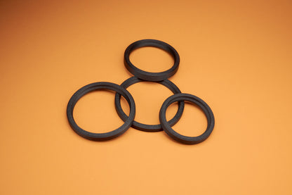 Five black Akara Labs Stealth rings laying on orange background
