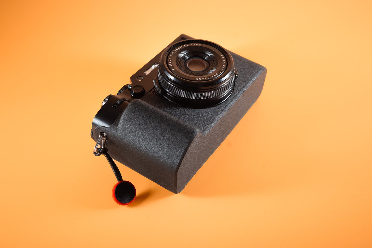 Fujifilm X100VI in black, angled bottom view, fitted with an Akara Labs Slim Skin standard case in black leatherette-textured TPU