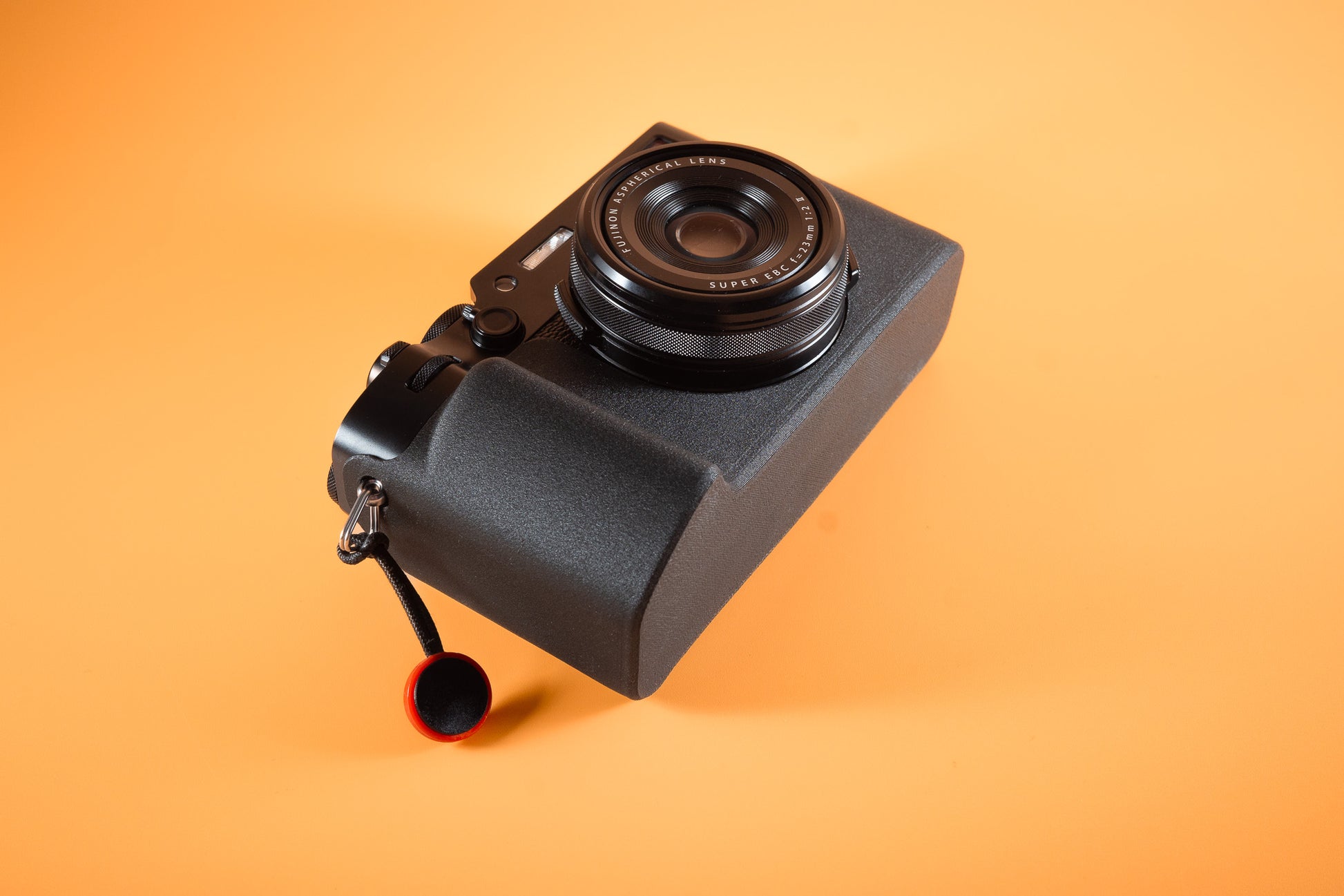 Fujifilm X100VI in black, angled bottom view, fitted with an Akara Labs Slim Skin standard case in black leatherette-textured TPU