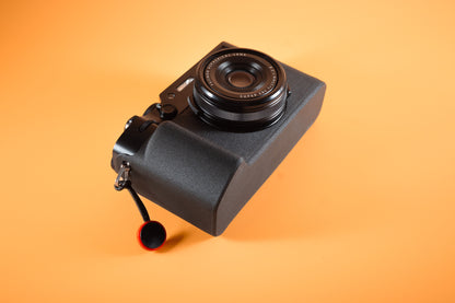 Fujifilm X100VI in black, angled bottom view, fitted with an Akara Labs Slim Skin standard case in black leatherette-textured TPU