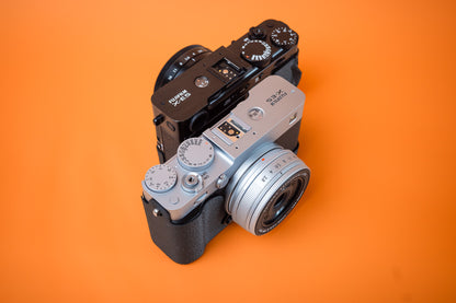 Fujifilm X-E5 in silver and black, angled view, fitted with an Akara Labs Slim Skin cases in black leatherette-textured TPU