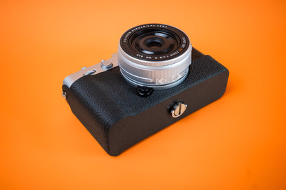 Fujifilm X-E5 in silver, bottom view, fitted with an Akara Labs Slim Skin tripod version case in black leatherette-textured TPU