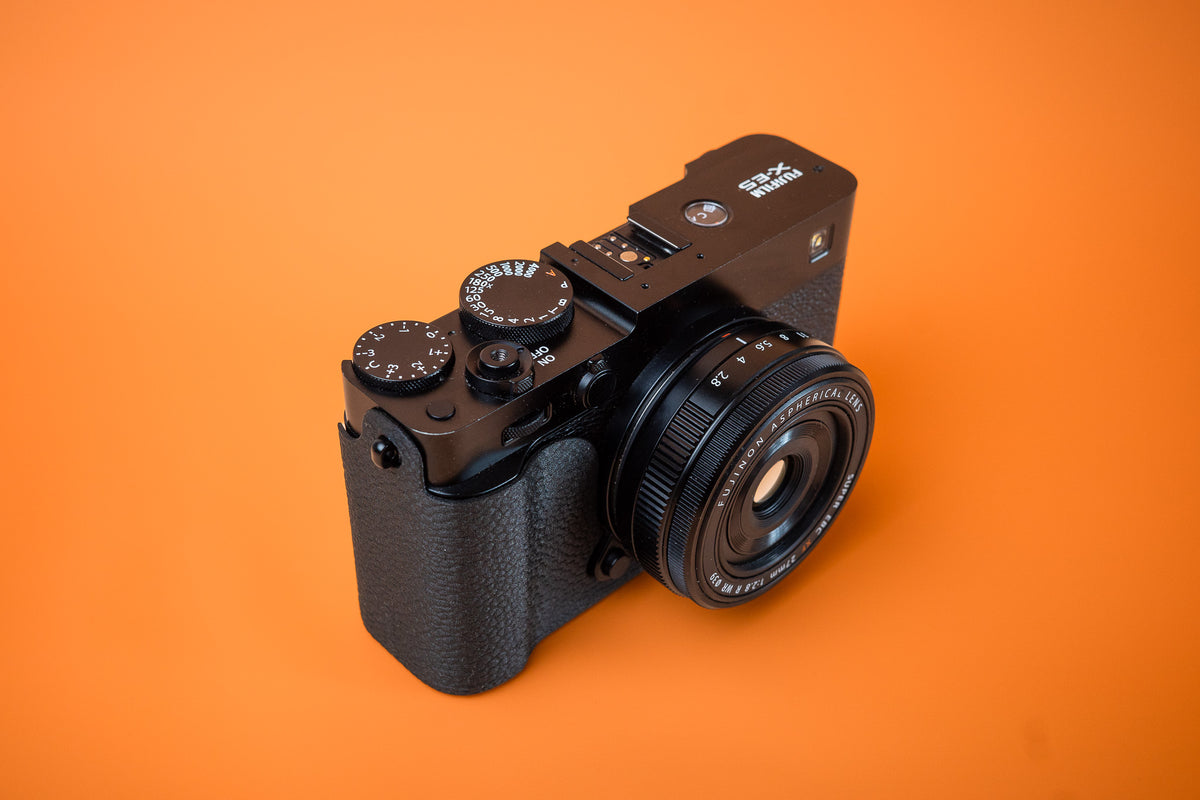 Fujifilm X-E5 in black, front right view, fitted with an Akara Labs Slim Skin case in black leatherette-textured TPU