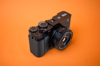 Fujifilm X-E5 in black, front right view, fitted with an Akara Labs Slim Skin case in black leatherette-textured TPU