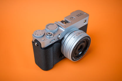 Fujifilm X-E5 in silver, front right view, fitted with an Akara Labs Slim Skin case in black leatherette-textured TPU