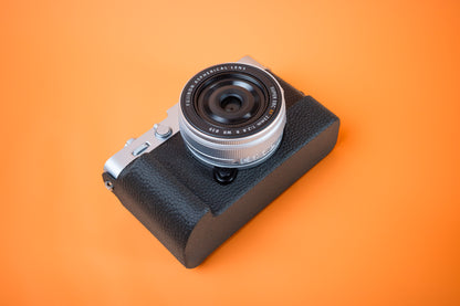 Fujifilm X-E5 in silver, front bottom view, fitted with an Akara Labs Slim Skin grip case in black leatherette-textured TPU