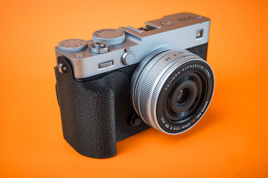 Fujifilm X-E5 in silver, front right view, fitted with an Akara Labs Slim Skin grip case in black leatherette-textured TPU