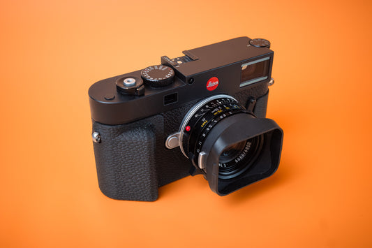 Leica M11 camera with Akara Labs Slim Skin Case. Grip standard version of case. Front right side. Orange background.