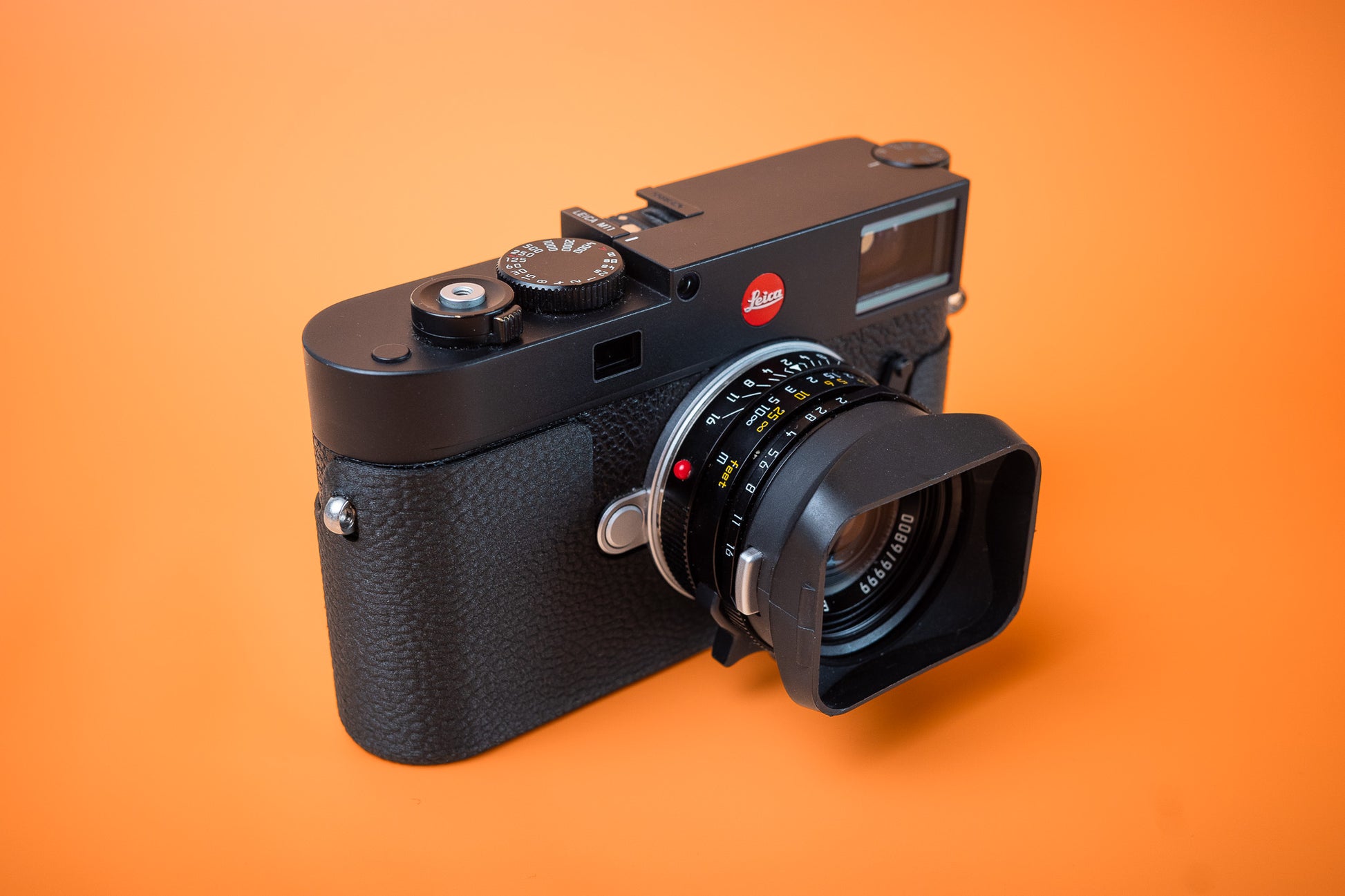 Leica M11 camera with Akara Labs Slim Skin Case. No Grip standard version of case. Front right side. Orange background.
