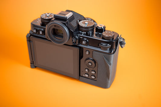 Nikon ZF TPU Slim Skin Case with thumb grip. Rear right of camera. Orange background.